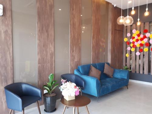 a living room with a blue couch and two chairs at Hotin Inn in Kuching