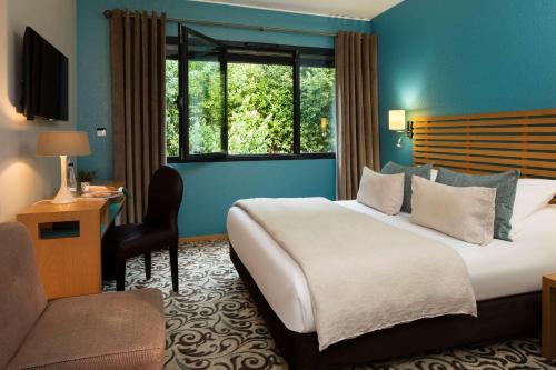 ナントにあるBest Western Plus Hotel De La Regate-Erdreの大きなベッドと窓が備わるホテルルームです。