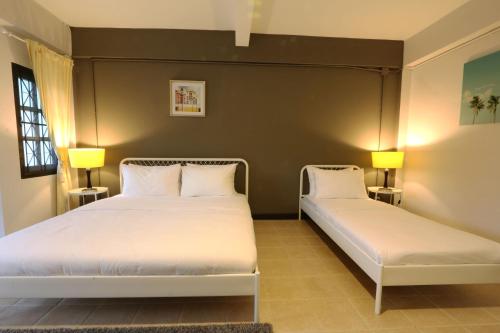 a bedroom with two beds and two lamps on the wall at Neveu Premier Residence : Ratchada in Bangkok