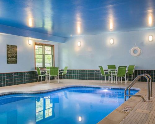 a pool in a hotel room with green chairs and a swimming pool at Econo Lodge Glens Falls - Lake George in Glens Falls