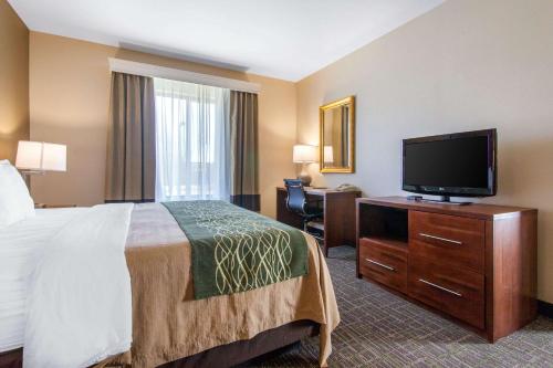 a hotel room with a bed and a flat screen tv at Comfort Inn & Suites Norman near University in Norman