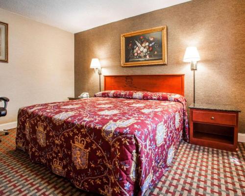 a hotel room with a bed with a red bedspread at Rodeway Inn in Paterson