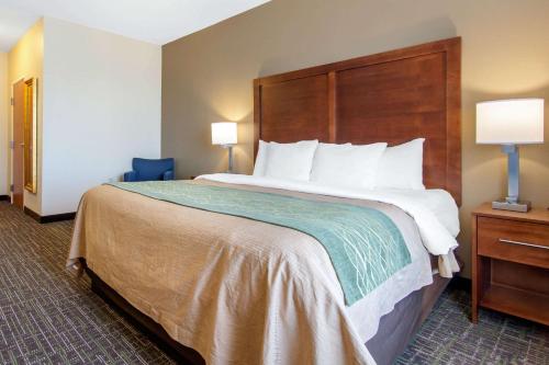 a hotel room with a large bed with a wooden headboard at Comfort Inn & Suites Norman near University in Norman