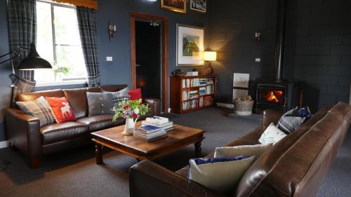 a living room with couches and a table and a fireplace at Troldhaugen Lodge - Adults Only in Jindabyne