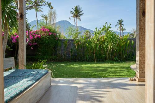 a patio with a view of a yard with flowers at Villa Coral in Pemuteran