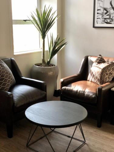a living room with two leather chairs and a table at Belaire Suites Hotel in Durban