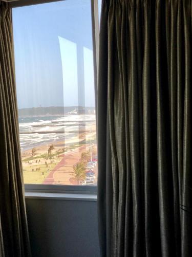 a window with a view of a beach and the ocean at Belaire Suites Hotel in Durban