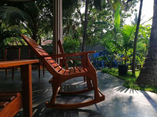 a wooden rocking chair sitting next to a table at Viveka Inn Guest and Yala Safari in Tissamaharama