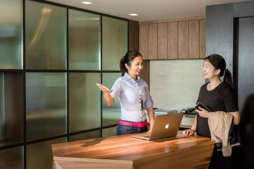 two women standing in an office with a table and a laptop at JEN Penang Georgetown by Shangri-La in George Town