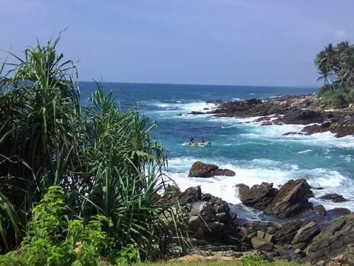 two people in a surfboard in the ocean at Mahee house in Hiriketiya