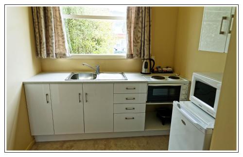 una pequeña cocina con fregadero y ventana en Lantern Court Motel, en Reefton