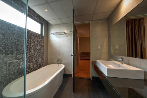 a bathroom with a tub and a sink at Acappella Suite Hotel, Shah Alam in Shah Alam