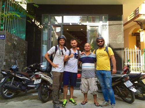 a group of men standing in front of a house at candyinn in Hue
