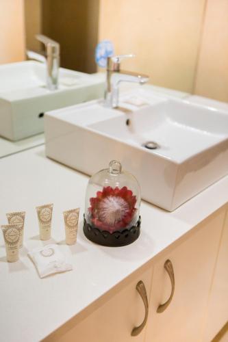 a bathroom counter with a sink and a glass jar with flowers at Skilpadvlei Wine Farm in Stellenbosch