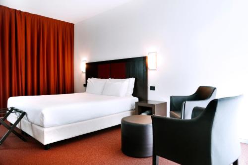 una camera d'albergo con letto e sedia di Hotel Holiday La Marca a Villorba