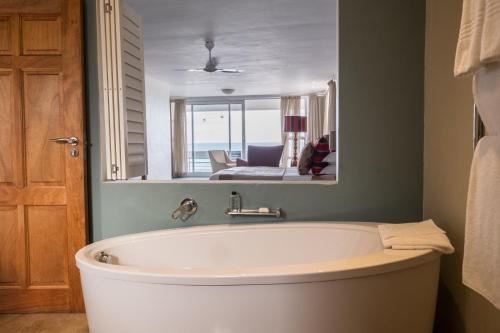 a bath tub in a bathroom with a mirror at Arniston Spa Hotel in Arniston