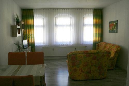 a living room with two chairs and a table and windows at Kleine Kirchgasse 28 in Annaberg-Buchholz