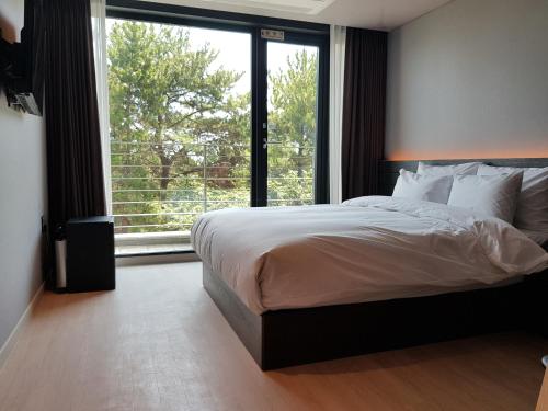a bedroom with a large bed and a large window at Suntree Hotel in Busan