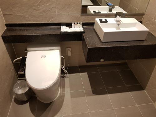 uma casa de banho com um WC branco e um lavatório. em Suntree Hotel em Busan