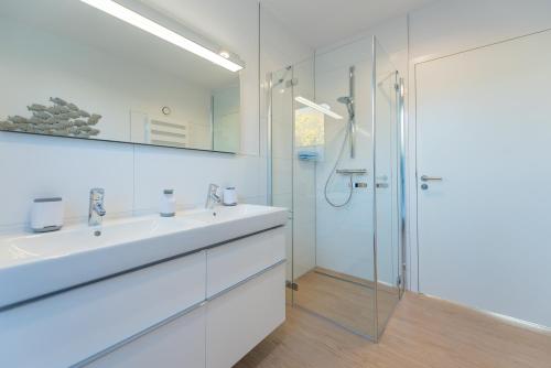 a white bathroom with a sink and a shower at Villa Granitzblick in Binz