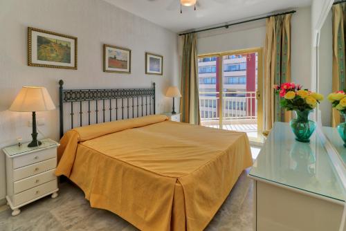 1 dormitorio con 1 cama y un jarrón de flores sobre una mesa en Doña Sofia en Fuengirola