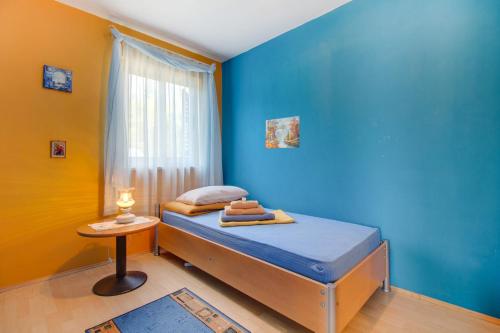 ein Schlafzimmer mit einem Bett mit einer blauen Wand in der Unterkunft Apartment Simpatico in Čunski