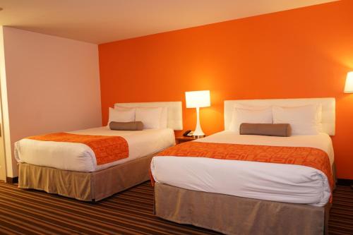 two beds in a hotel room with orange walls at Howard Johnson by Wyndham Salinas in Salinas