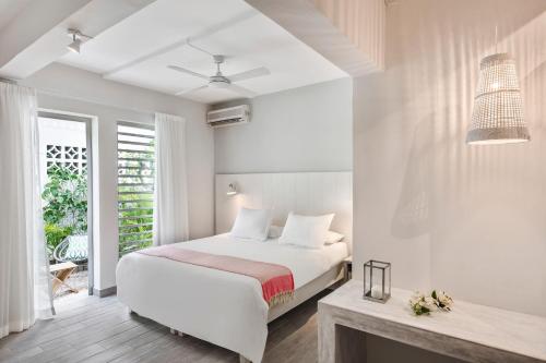a white bedroom with a bed and a window at The Bay in Rivière Noire