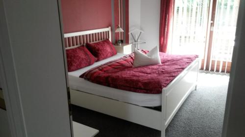 1 dormitorio con 1 cama con sábanas rojas y espejo en Haus Backbord, Wohnung Hauptdeck, en Fehmarn