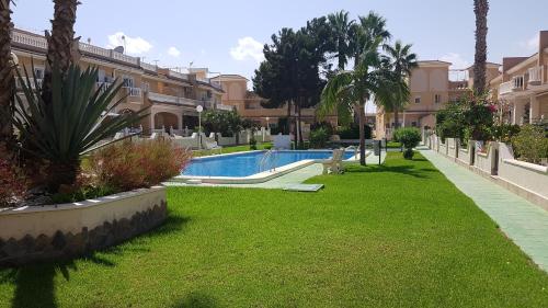 a resort yard with a swimming pool and palm trees at Casa Palma in Los Alcázares
