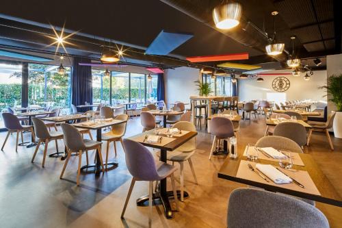 un restaurant avec des tables, des chaises et des fenêtres dans l'établissement ibis Styles Evry Lisses, Évry-Courcouronnes