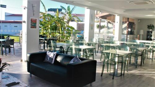 a black couch in a restaurant with tables and chairs at Silver Seahorse Garden Retreat in Peniche