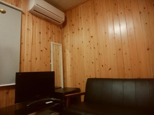 a room with wooden walls and a couch and a television at Asumi Onsen in Fujiyoshida