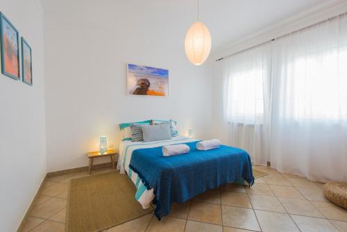 1 dormitorio con 1 cama con manta azul en By the C house, en Vila Nova de Milfontes