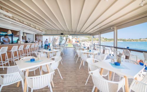 a restaurant with white tables and chairs on a cruise ship at Filoxenia Beach in Tsilivi