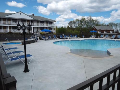 a swimming pool in a resort with chairs and umbrellas at Mariner Resort in Ogunquit