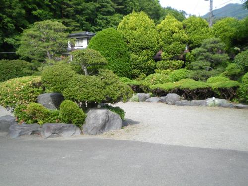 a garden with rocks and trees and a house at Asumi Onsen in Fujiyoshida