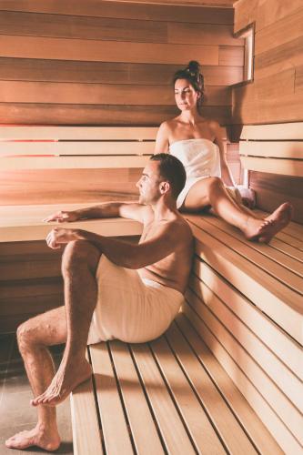 a man and woman sitting in a sauna at Hotel de Sterrenberg - Adults Only in Otterlo