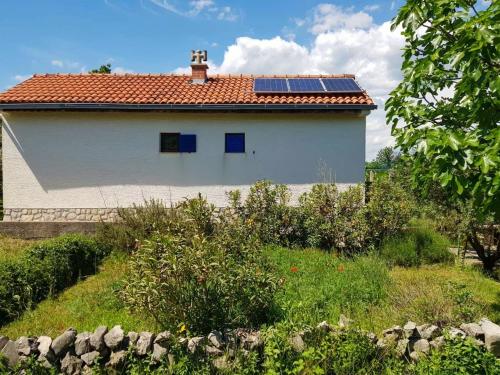 ein Haus mit einem Dach mit Sonnenkollektoren darauf in der Unterkunft Ecohouse Oliveglia in Šilo