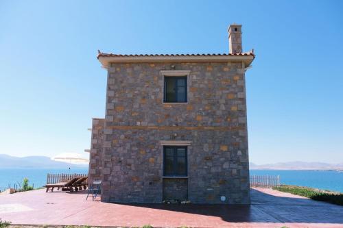 a stone building with the ocean in the background at Fanaraki villas in Moudhros