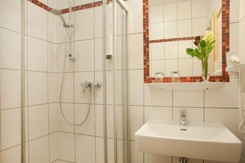 La salle de bains blanche est pourvue d'une douche et d'un lavabo. dans l'établissement Hubertushof Fromwald Hotel und Gasthof, à Bad Fischau