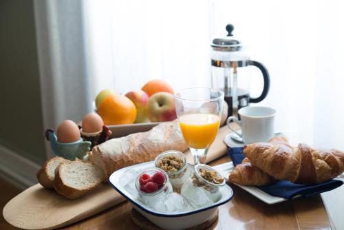 uma bandeja de pequeno-almoço com ovos, pão, fruta e um copo de sumo de laranja em Le Petit Cochon em Valence-sur-Baïse