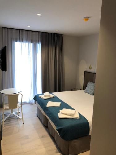 a bedroom with a bed with two towels on it at HOTEL TORRENT in L'Escala