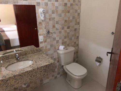 a white toilet sitting next to a sink in a bathroom at Pousada Le Sapê in São Lourenço
