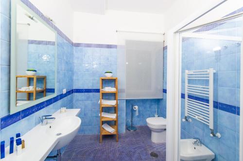 a blue tiled bathroom with a sink and a toilet at Residence Due Torri in Maiori