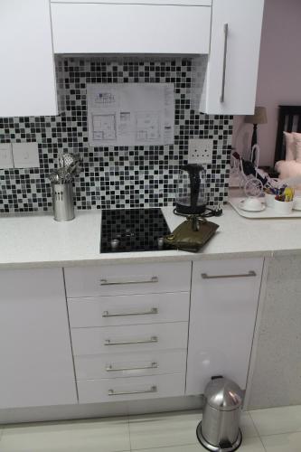 a kitchen with white cabinets and black and white tiles at Pat Luxurious Studio in Gaborone