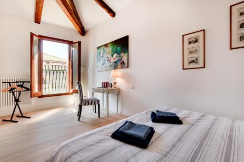 1 dormitorio con cama, escritorio y ventana en San Marcuola apartment, en Venecia