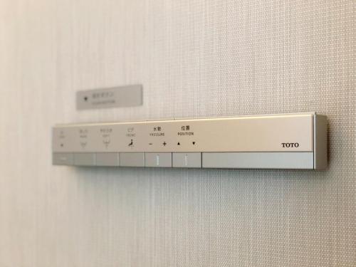a shelf on a wall with a temperatureimeter on it at Hotel Comfact in Tokyo