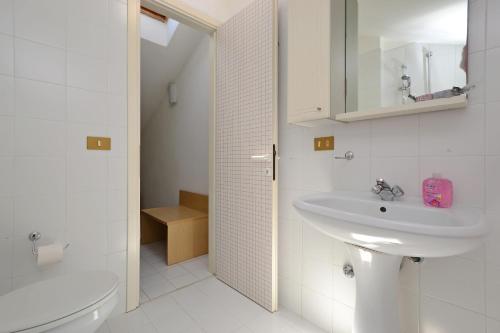 a white bathroom with a sink and a toilet at Parco Hemingway in Lignano Sabbiadoro