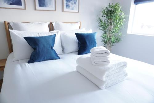 ein weißes Bett mit blauen Kissen und Handtüchern darauf in der Unterkunft Saltwater Newquay in Newquay